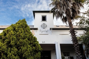 Ein Gebäude mit weißer Fassade, einem schwarzen Fensterrahmen und der deutlich sichtbaren Nummer 165.