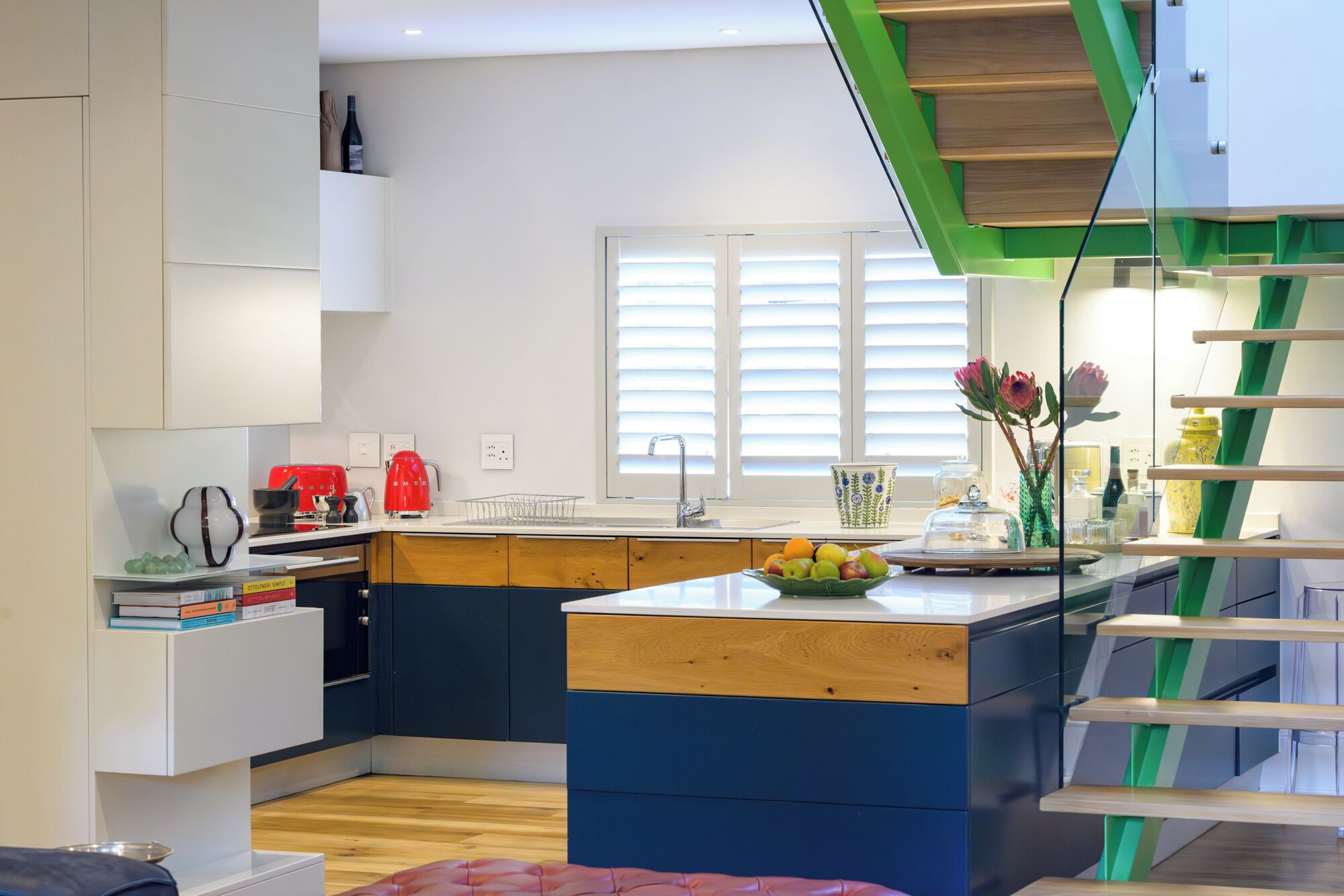 Een moderne keuken met een centraal eiland, een ingebouwde oven en een raam met zonwering.