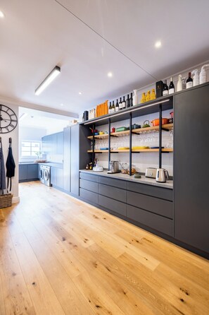 A modern kitchen with grey cabinetry, wooden flooring, and a variety of kitchenware and appliances. - Rozenhof Villas (Stellenbosch)