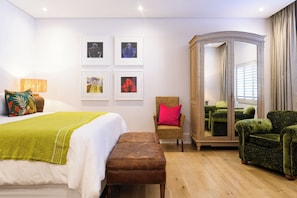 Ein Hotelzimmer mit Bett, einem Sessel, einem Kleiderschrank und Bildern an der Wand.
