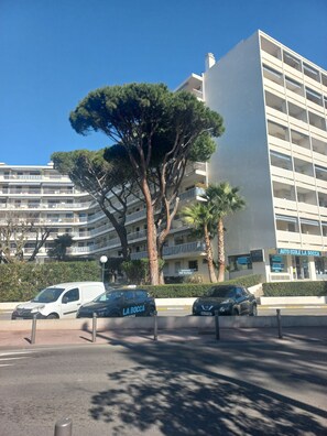 A multi-story building with balconies, a parking area with cars, and a large tree in the foreground. - 3-room apartment in Cannes, 250 m from the beach. Close to all shops. 100-150 m (Cannes)