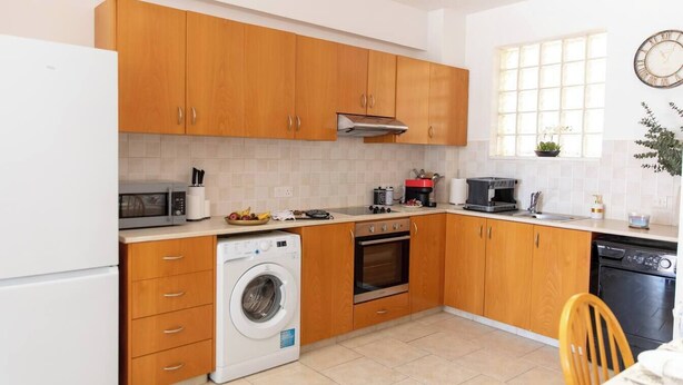 Uma cozinha compacta com armários de madeira, máquina de lavar, micro-ondas e lava-louças.