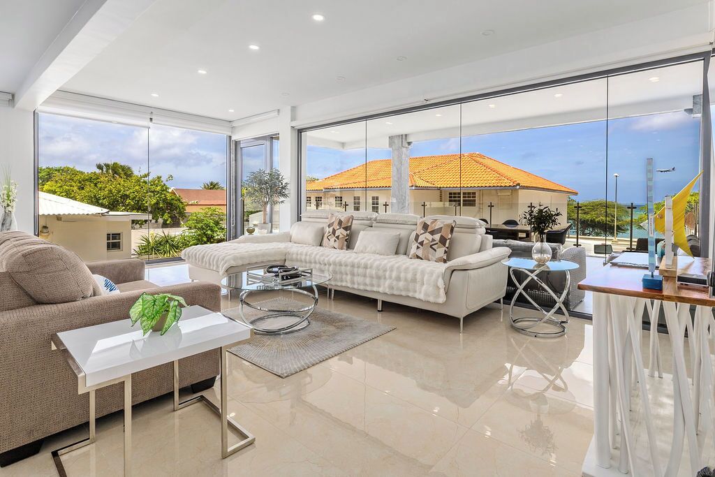 Settle into your bright, modern living space where floor-to-ceiling windows frame coastal views and gentle breezes flow through. Your open, sunlit sanctuary invites relaxation with sleek furnishings and serene elegance.