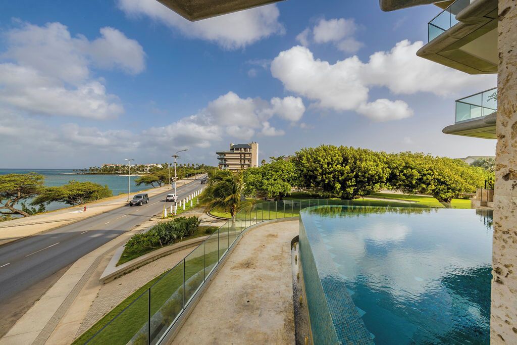 Un hôtel moderne doté d’une piscine donnant sur une route et un plan d’eau.