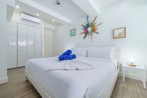 Ein Hotelzimmer mit einem Bett, weißen Wänden, einem Deckenventilator und einem Wanddekor.