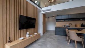 A modern kitchen with a built-in TV, wooden paneling, and a dining area with a table and chairs. - Apartamenty Sun & Snow Wisła View (Wisła)