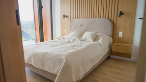 A bedroom with a bed, wooden headboard, and a view through a window.