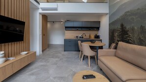 Uma sala de estar moderna com televisão de tela plana, um sofá, uma mesa de centro e um espaço de jantar com mesa e cadeiras.