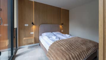 A modern bedroom with a bed, bedside tables, and a glass partition.
