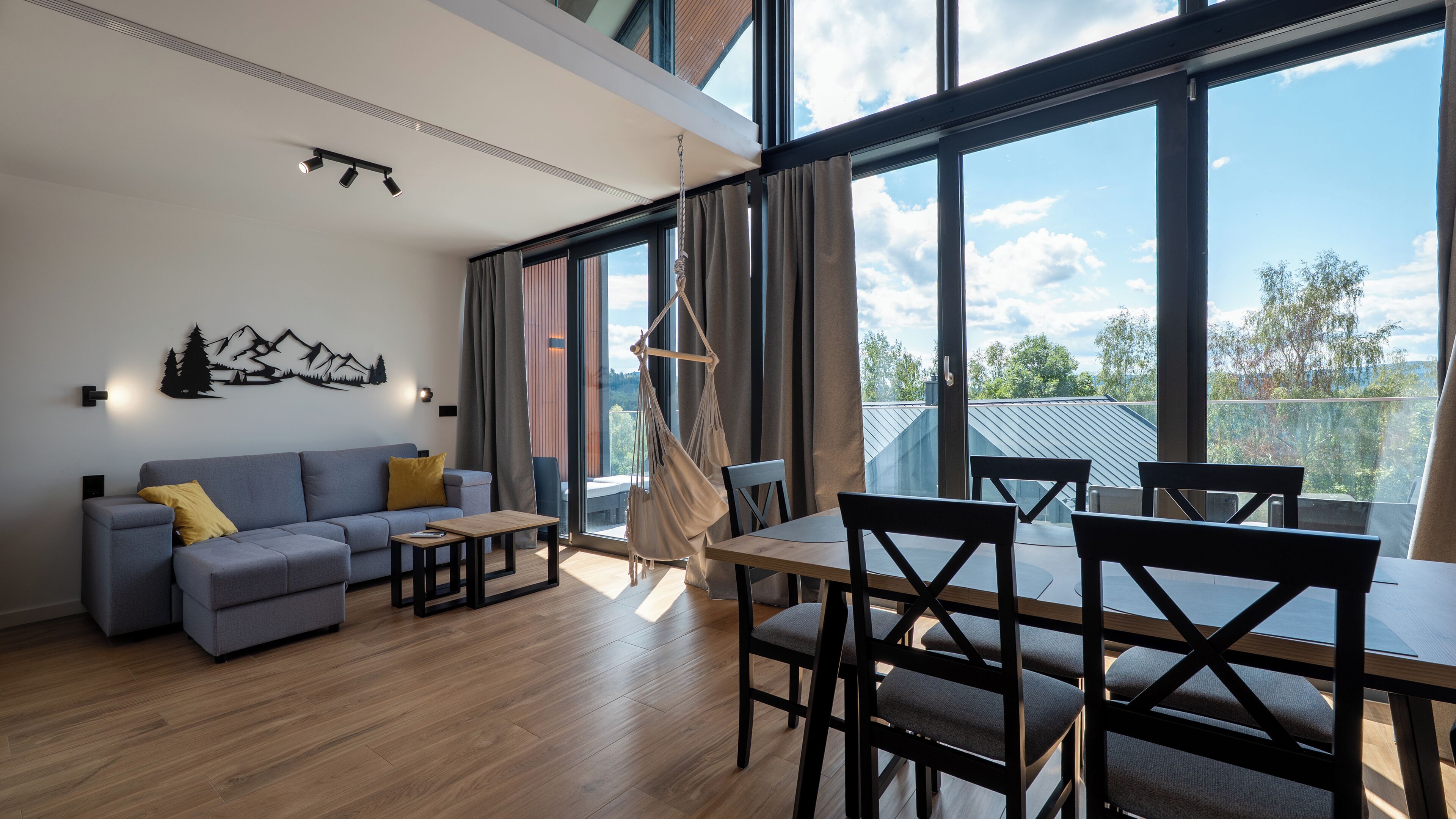 Un salon moderne comprenant un canapé, une table basse et un coin repas avec des chaises.
