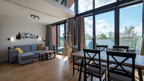 A modern living room with a sofa, coffee table, and dining area with chairs.