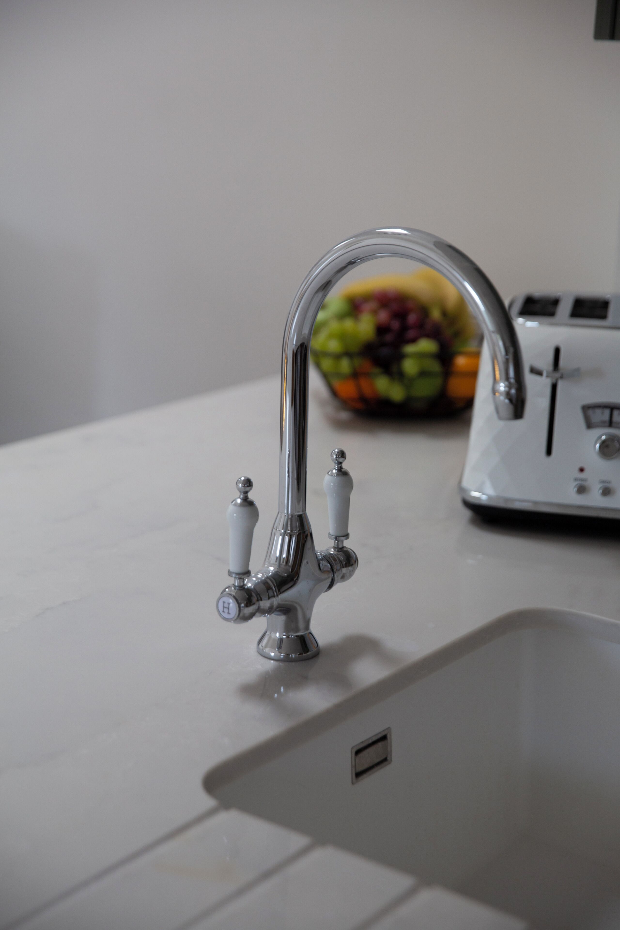 A kitchen sink with a modern faucet and a toaster in the background.