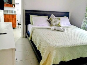 A neatly made bed with a white comforter and pillows, a wooden headboard, and a white bedside table. - Your Jamaican Getaway | Summer Breeze Villa with Pool & Gym Access (Lucea)