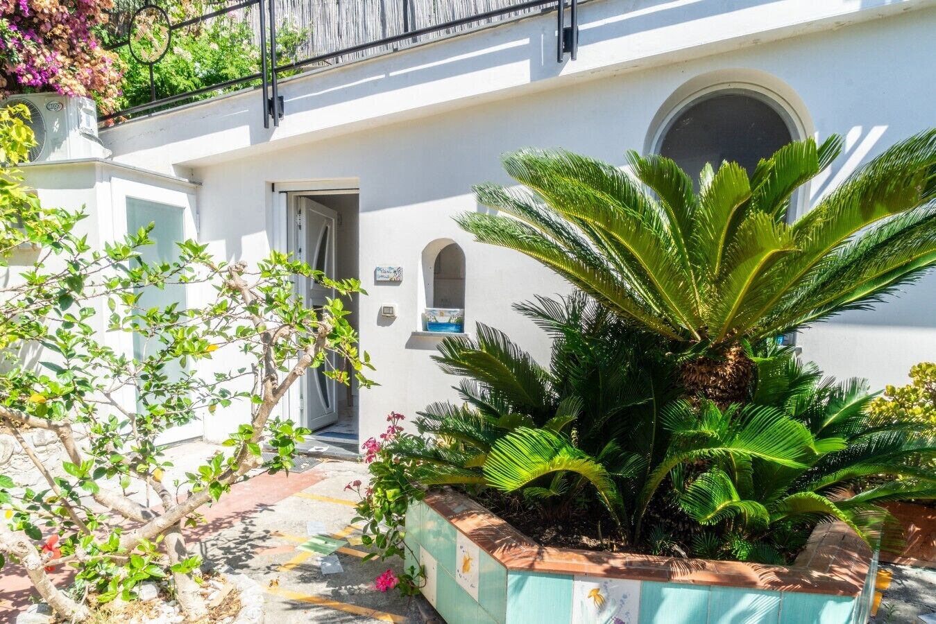 Un bâtiment blanc avec une porte, une fenêtre et un petit balcon.