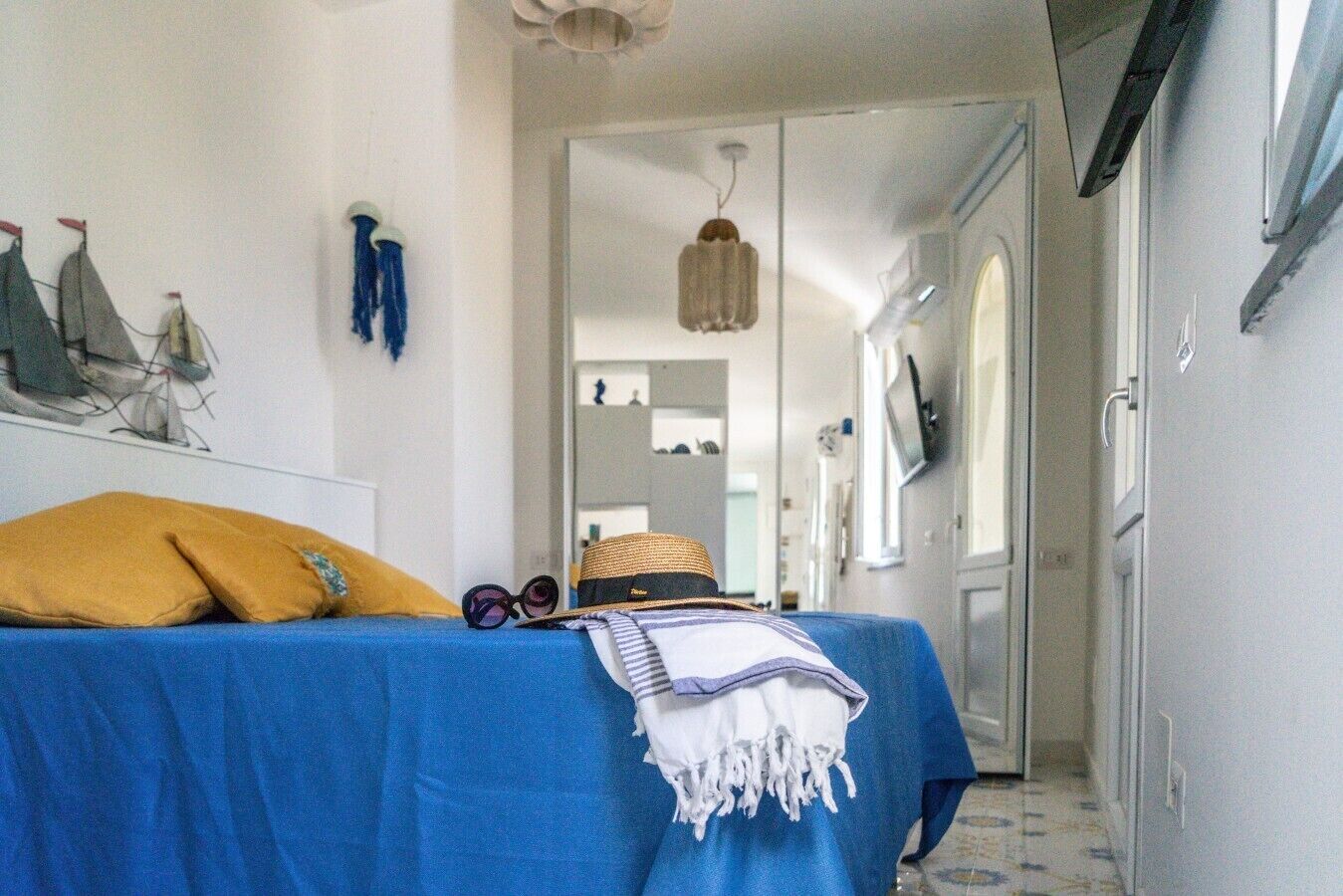 Une chambre avec un lit, un chapeau, des lunettes de soleil et une serviette posée sur le lit.
