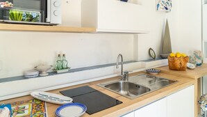 Une cuisine moderne équipée d’un évier en acier inoxydable, d’un four à micro-ondes et d’une variété d’ustensiles de cuisine.