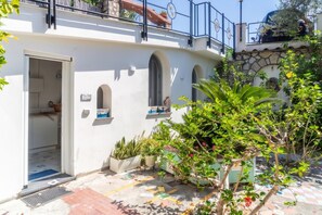 A building with a white exterior, arched windows, and a balcony with a railing. - Naos Nerano - Elegance & Comfort (Nerano)
