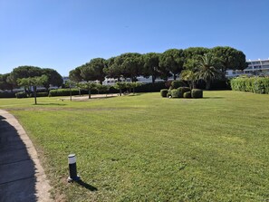 A well-maintained grassy area with a pathway, benches, and neatly trimmed bushes. - Studio apartment with a loggia near the ocean (Le Grau-du-Roi)
