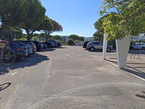 A parking lot with multiple cars and a bicycle. - Studio apartment with a loggia near the ocean (Le Grau-du-Roi)