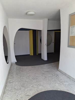 A corridor with white walls, a marble floor, and a door with a circular window. - Studio apartment with a loggia near the ocean (Le Grau-du-Roi)
