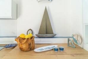 Une table en bois sur laquelle se trouve un saladier rempli de citrons, un petit voilier décoratif et une maquette de bateau.