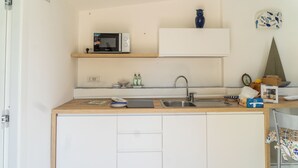 A compact kitchen with a microwave, sink, and a small cabinet above the countertop. - Naos Nerano (Nerano)
