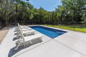 Piscina com espreguiçadeiras e cerca.