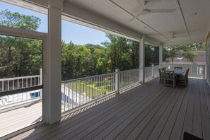 A covered outdoor area with a table and chairs, a railing, and a view of a green landscape. - Private Pool, Elevator, Close to Beach, New Construction, King Beds, SS0298 (Southern Shores)