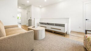 En moderne stue med en sofa, et sofabord og et hvidt tv-møbel.