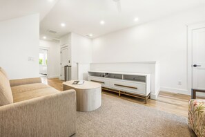 Ein modernes Wohnzimmer mit einer Couch, einem Couchtisch und einer weißen Unterhaltungseinheit.