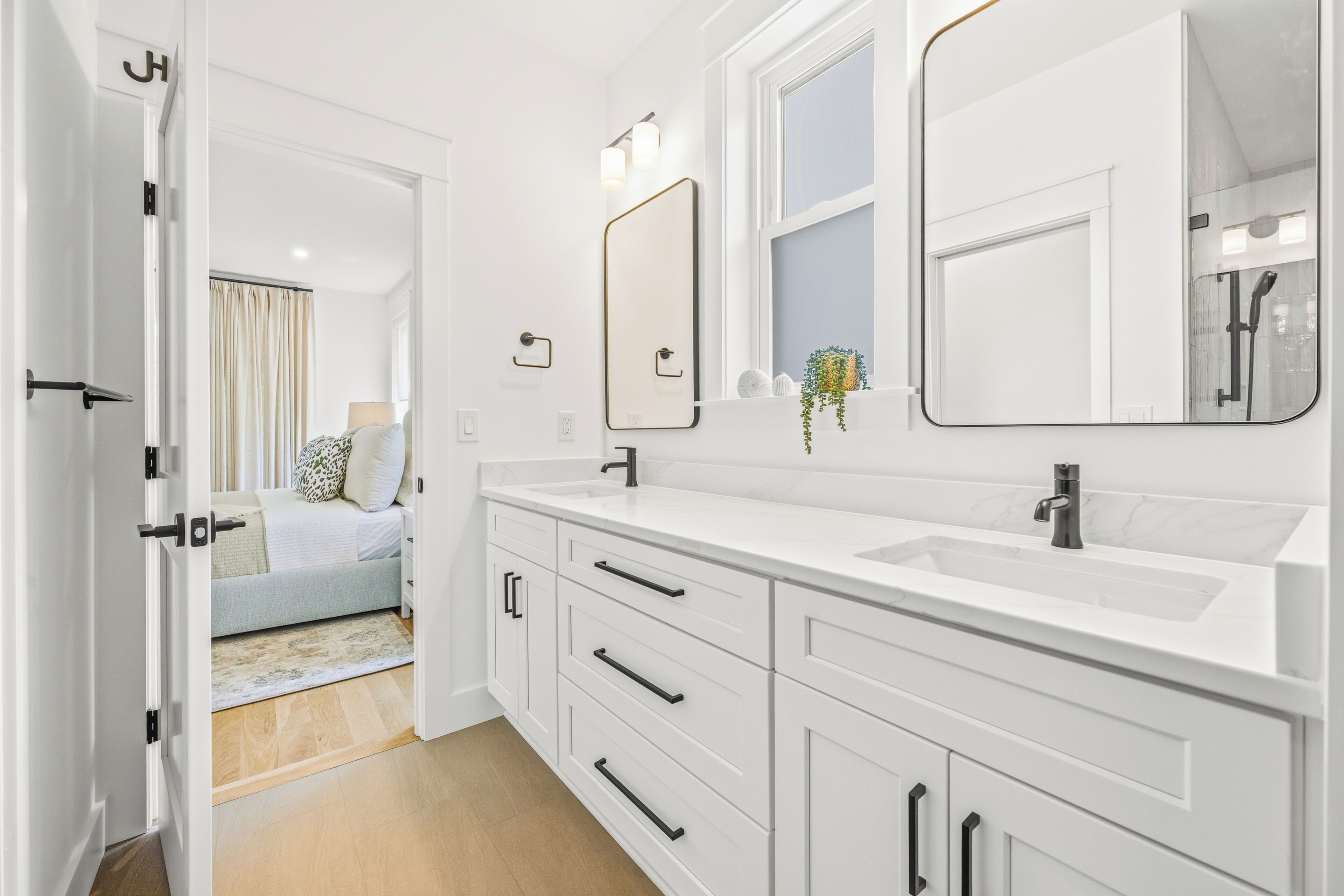 A modern bathroom with two sinks, a large mirror, and a shower area.