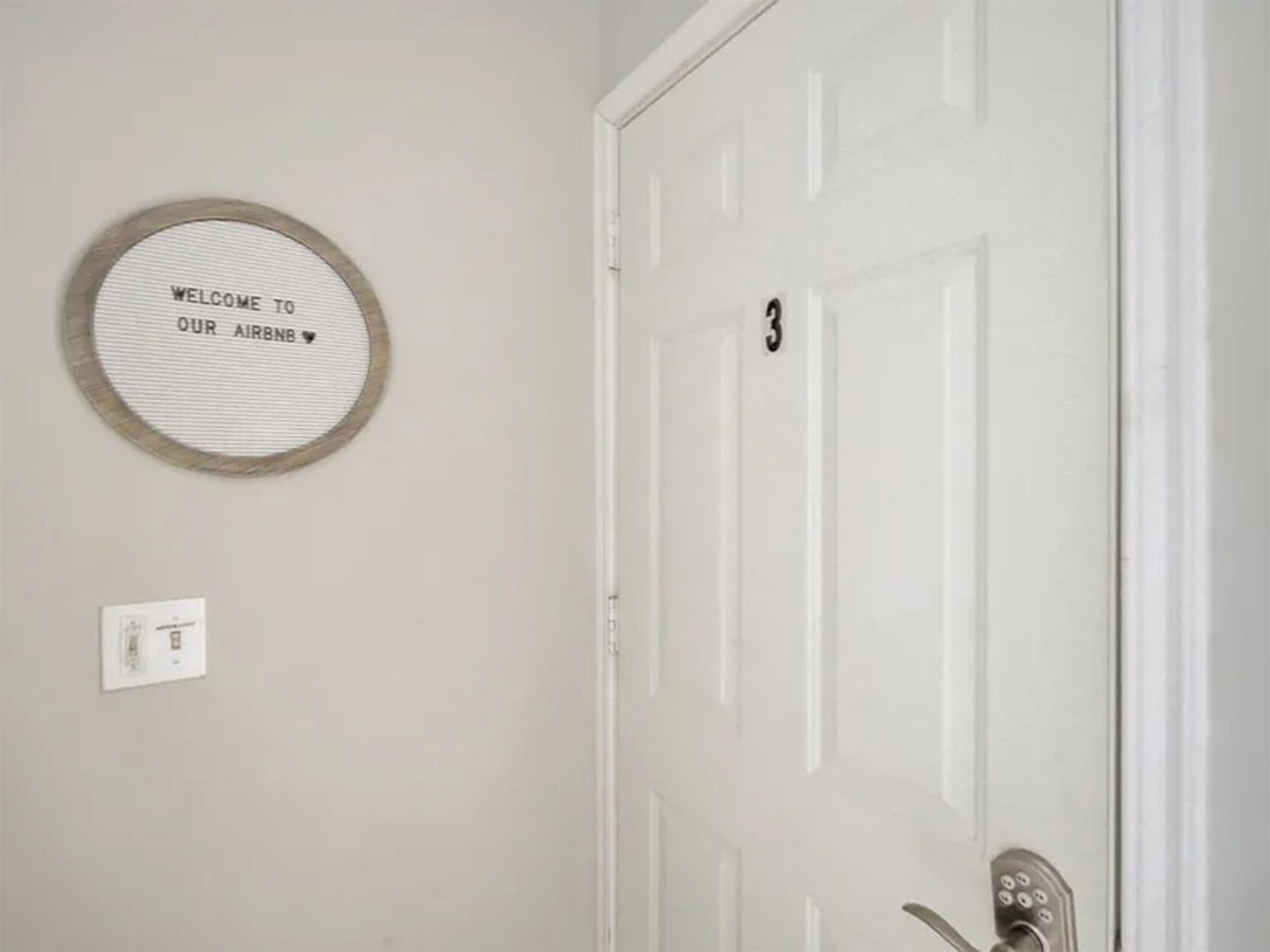 A door with a number '3' and a circular sign above it that reads 'WELCOME TO OUR AIRBNB.'
