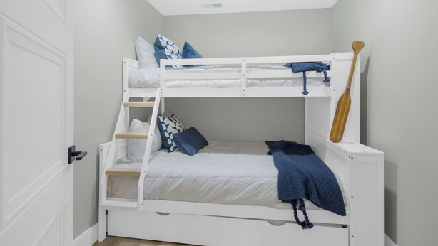 Ein Stockbett mit Holzleiter, eine weiße Tür und ein an der Wand befestigtes Holzstöckchen.