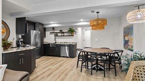 Eine moderne Küche mit dunklen Schränken, Edelstahlgeräten und einem Holzespeisesaal mit schwarzen Stühlen.