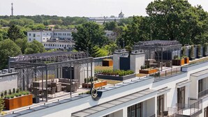 Un edificio moderno con varios balcones, jardines en la azotea y una vista despejada del paisaje urbano.