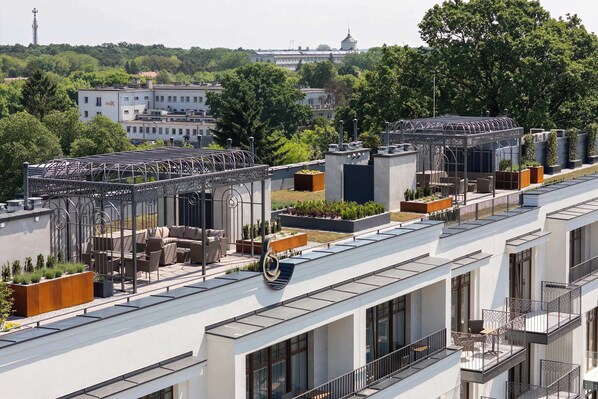 A modern building with multiple balconies, rooftop gardens, and a clear view of the surrounding cityscape.