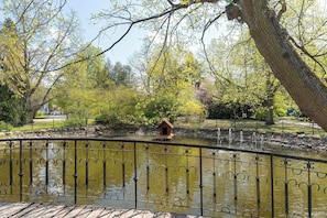 A park with a pond, a wooden bridge, and a metal fence. - Luxury Studio with Air Conditioning | Balcony | Roof Terrace (Ciechocinek)