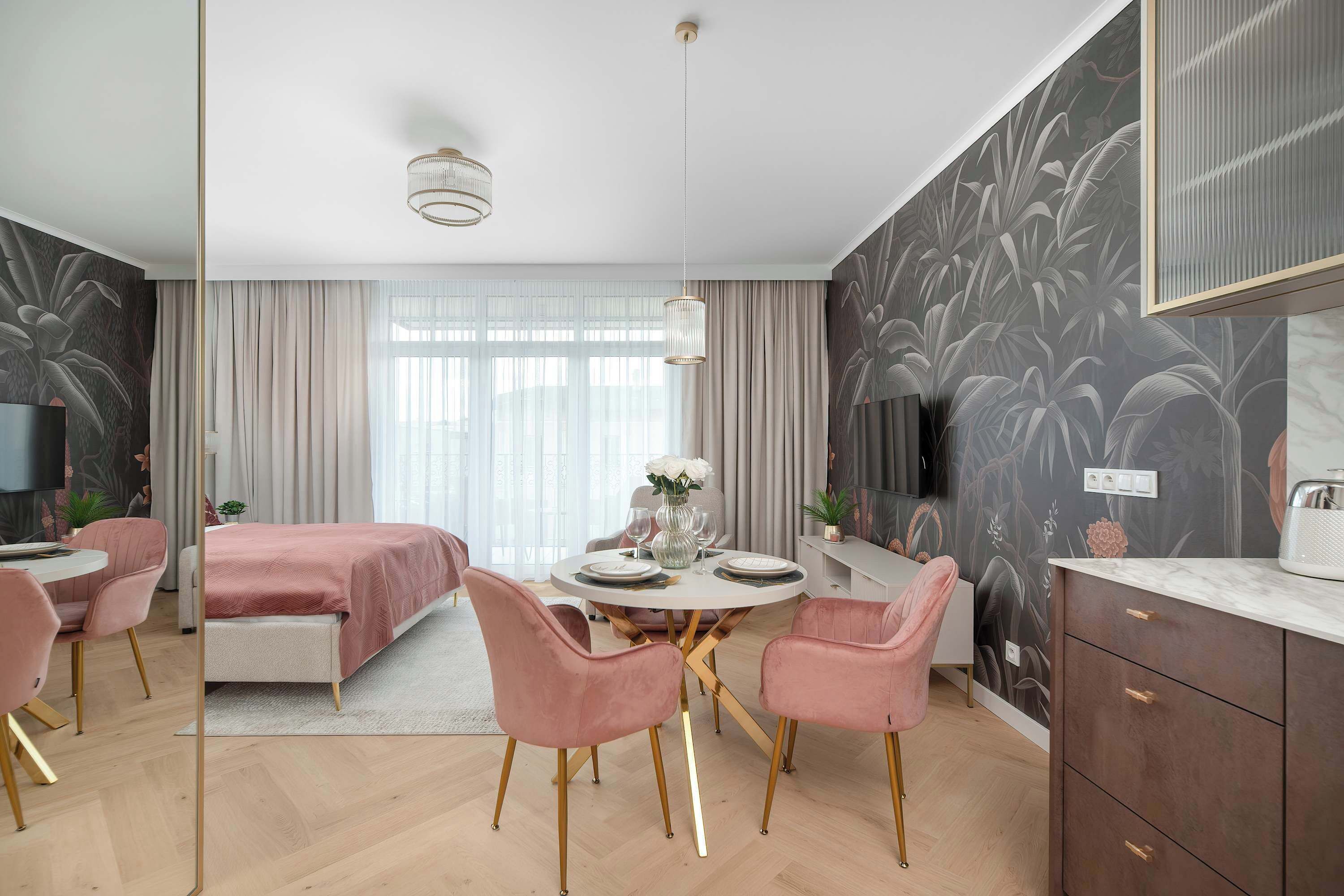 Un dormitorio moderno con una cama, una mesa de comedor con sillas, un televisor y un ventanal grande.