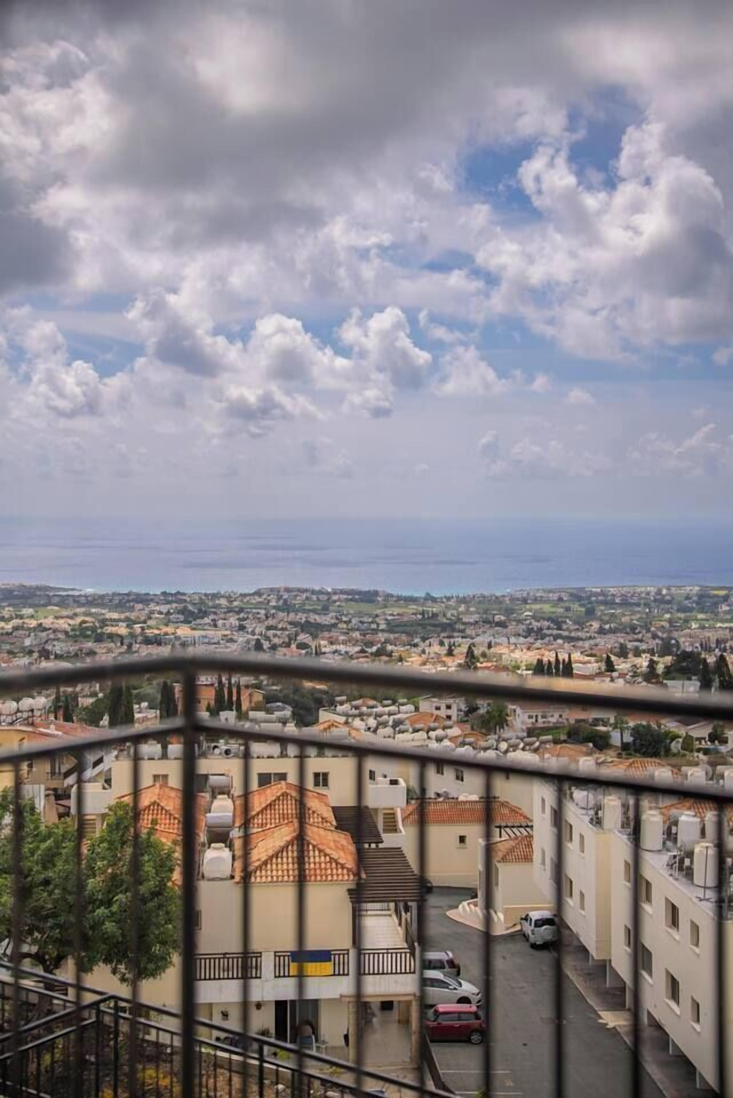 A residential area with buildings, a clear sky, and a distant view of the sea.