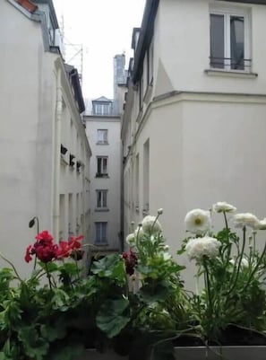 A narrow urban alleyway with buildings on either side, featuring a small window and a balcony. - Beautiful, Air-Conditioned Apartment in Aix, Right in the Heart of Downtown (ile de france)