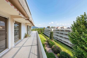 A modern building with a balcony overlooking a neatly landscaped garden and a distant view of a cityscape. - Somptuous 3-BR Penthouse - Pool & Ocean View - Saint-Tropez (Saint-Tropez)
