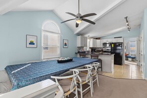 Una cocina moderna con armarios blancos, un refrigerador negro y un comedor con mantel estampado azul.