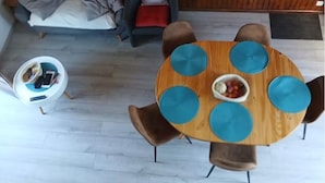 A room with a round wooden table with blue accents, a sofa, and a chair.