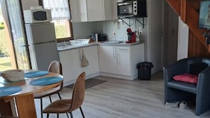 A compact kitchen with white cabinets, a microwave, and a red coffee machine.