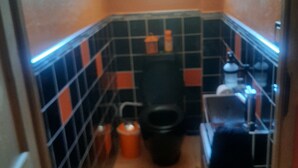 Pieni kylpyhuone, jossa on wc, pesuallas ja laatoitetut seinät.