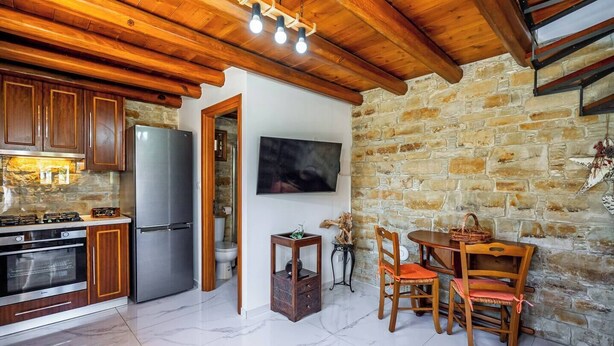 Eine Küche mit Holzausstattung, einem Kühlschrank, einem Herd und einem Essbereich mit Tisch und Stühlen.