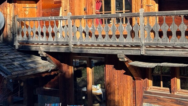 A wooden chalet with a balcony, stone flooring, and a rustic aesthetic. - The Red Room (Demi-Quartier)