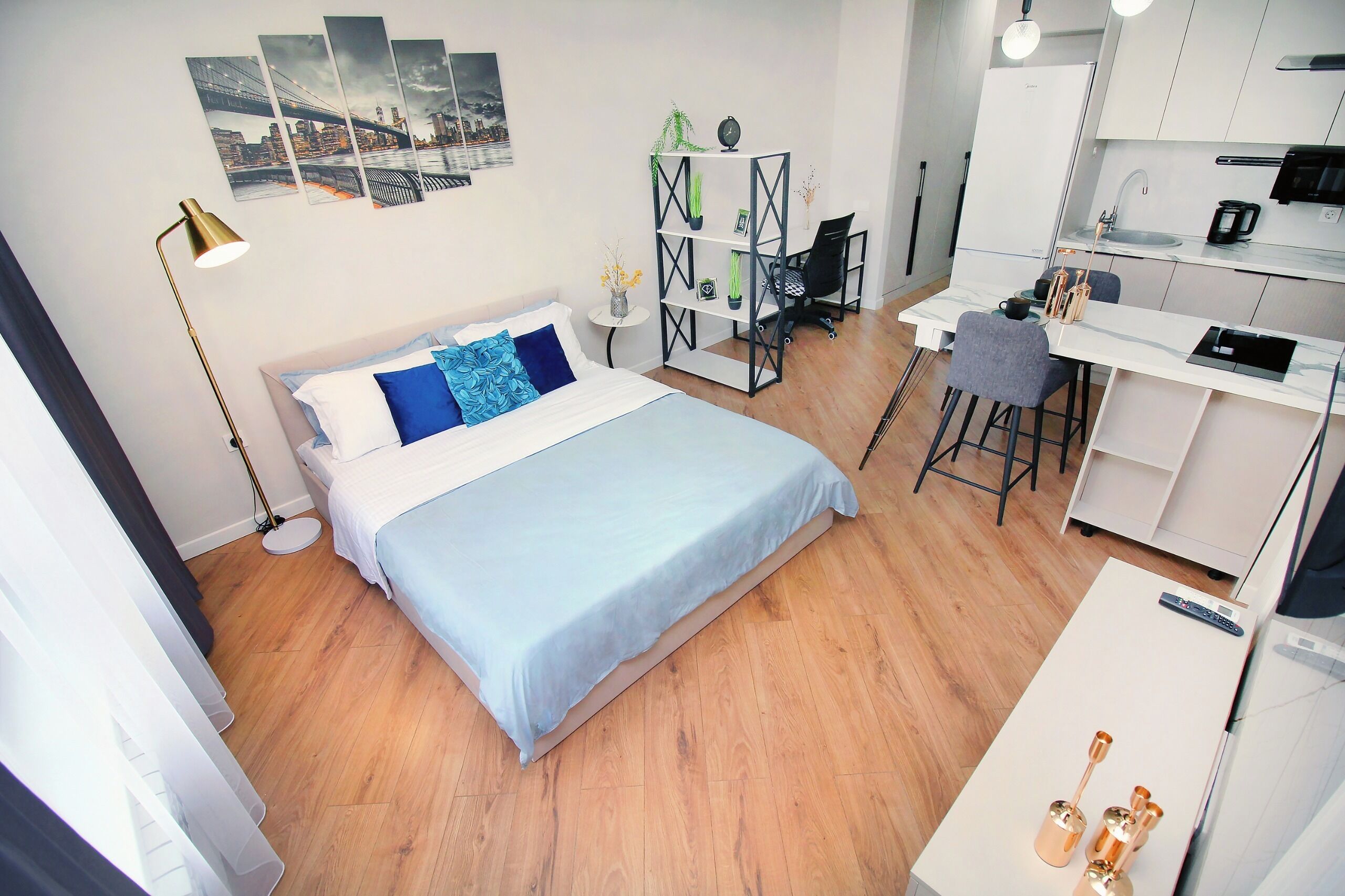 Una habitación de hotel moderna con una cama, un escritorio, una silla y una kitchenette.