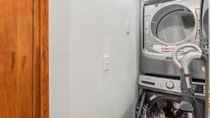 Ein Waschraum mit Waschmaschine und Trockner, einer Holztür und einer weißen Wand.