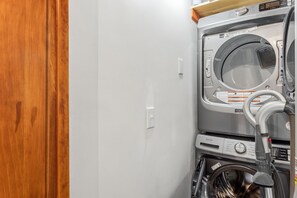 A laundry room with a washing machine and dryer, a wooden door, and a white wall. - The Rendezvous Chalet – Spacious Mountain Retreat (Breckenridge)